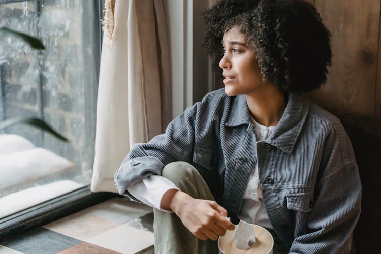 Black Woman Crying From Grief Sitting With Box Of Tissues