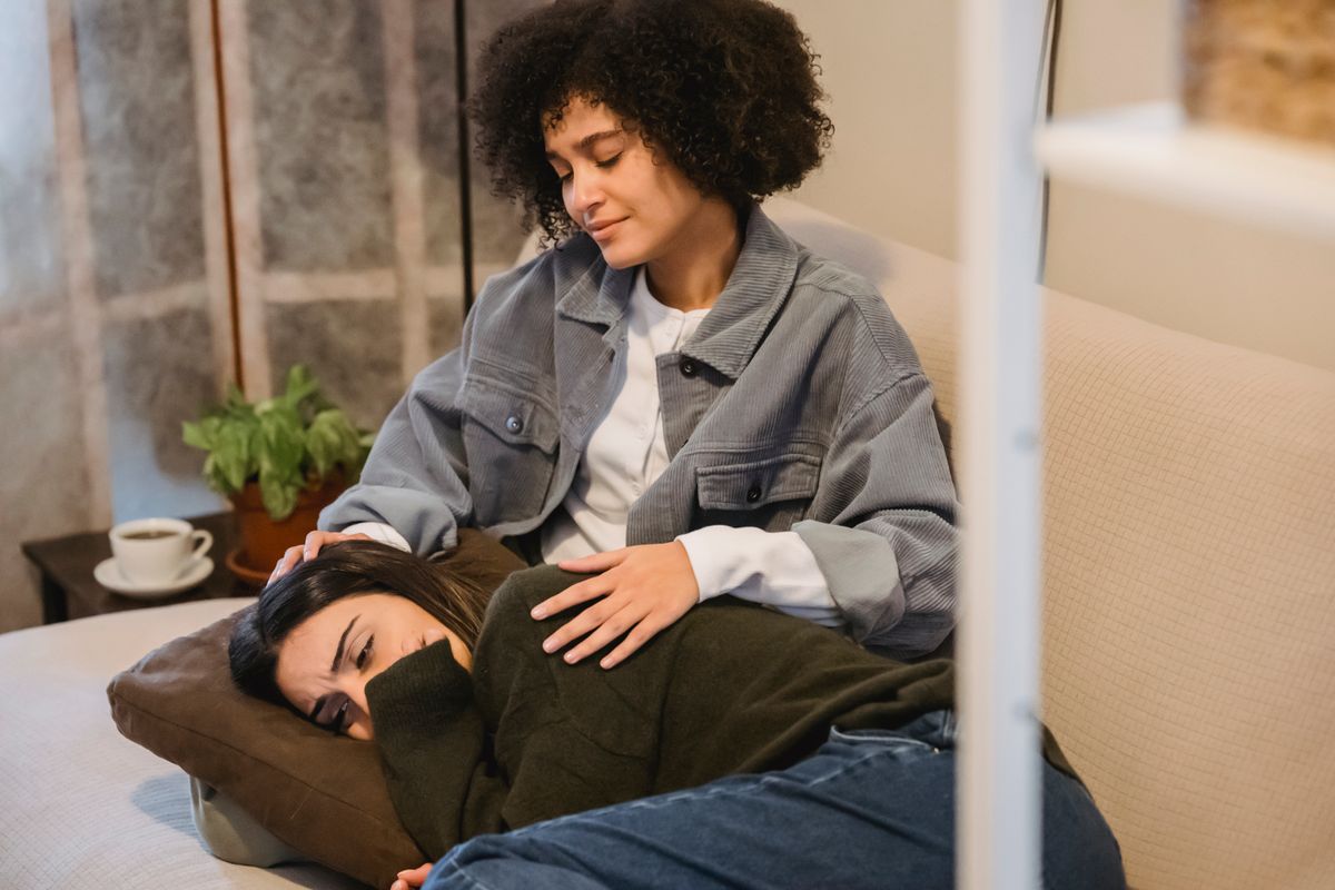 Young woman gently comforting a friend who rests her head in her lap