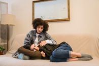 Young black woman supporting crying female friend on couch