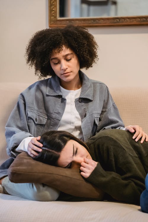 Free Ethnic woman lying on knees of black female friend and crying Stock Photo