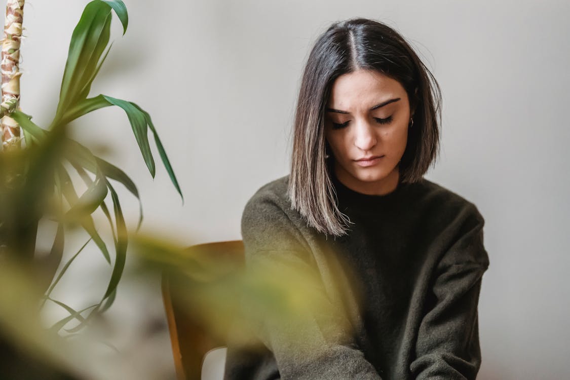 Woman in Black Turtleneck Sweater Sitting on Brown Wooden Chair