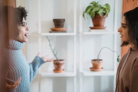 Side view of African American female yelling at woman while looking at each other during conflict in room with green plants