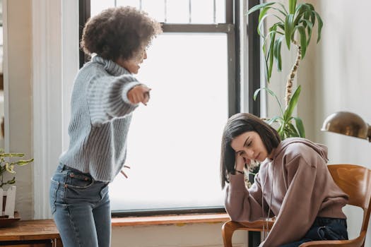 Two women having an intense emotional conversation indoors, involving expressions of frustration.