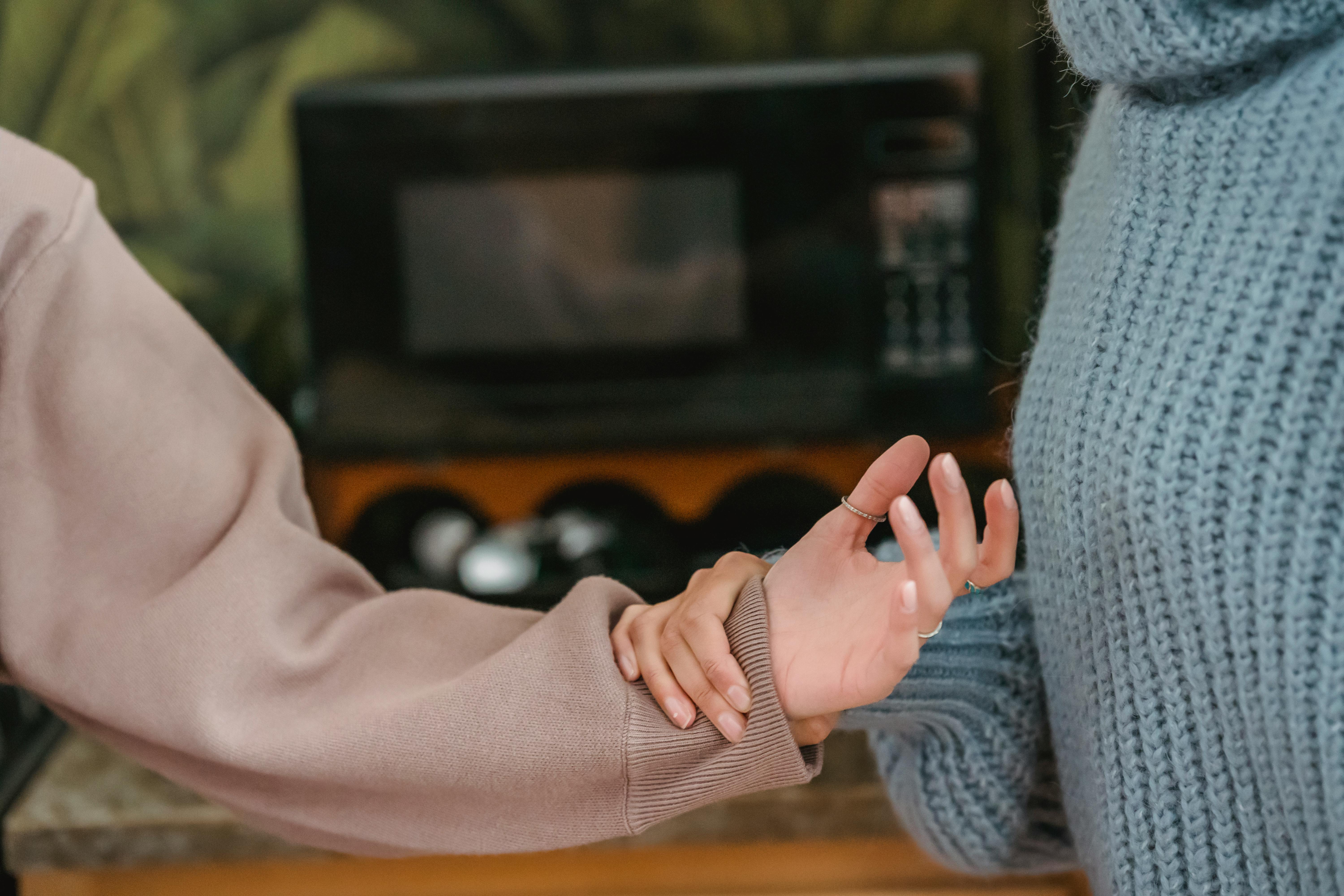Close-up of hands showing one person grasping another's wrist, representing the physical manifestation of controlling behavior and manipulation tactics.