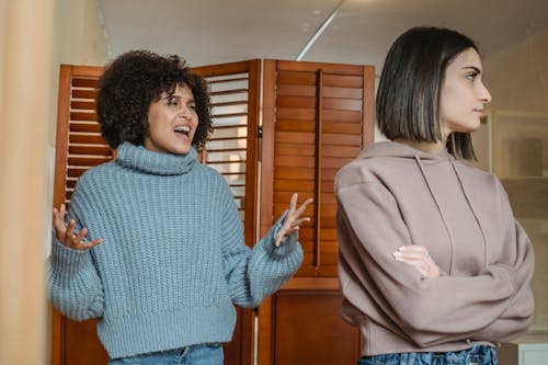 Wanita Dengan Sweater Biru Berdiri Di Samping Wanita Dengan Mantel Coklat