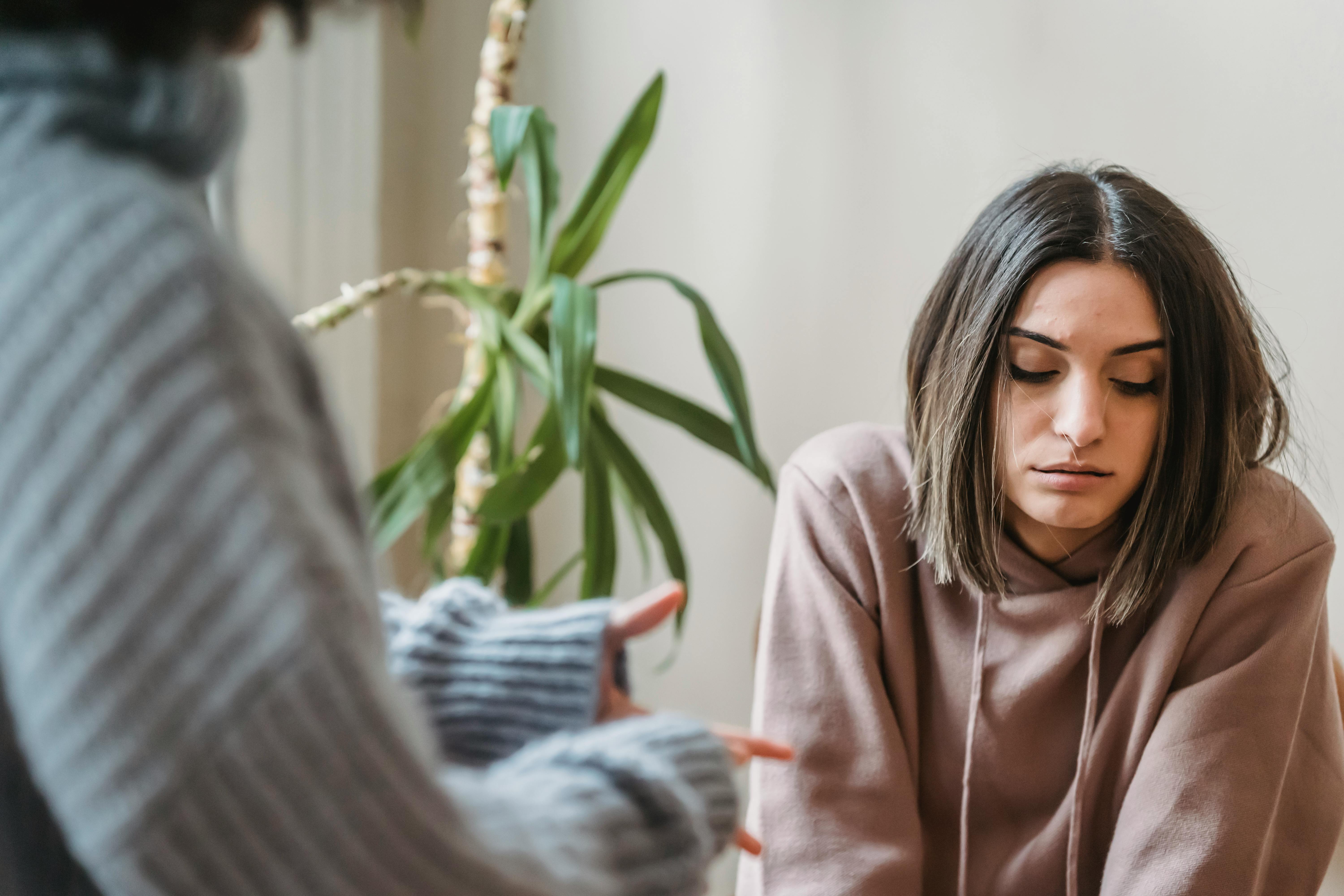 A woman looks away from another during a conversation. This represents how to deal with conflict anxiety and how it can make us withdrawn instead of speaking up. 