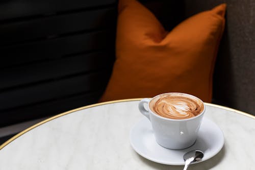 Cup of cappuccino served on table in modern cafeteria