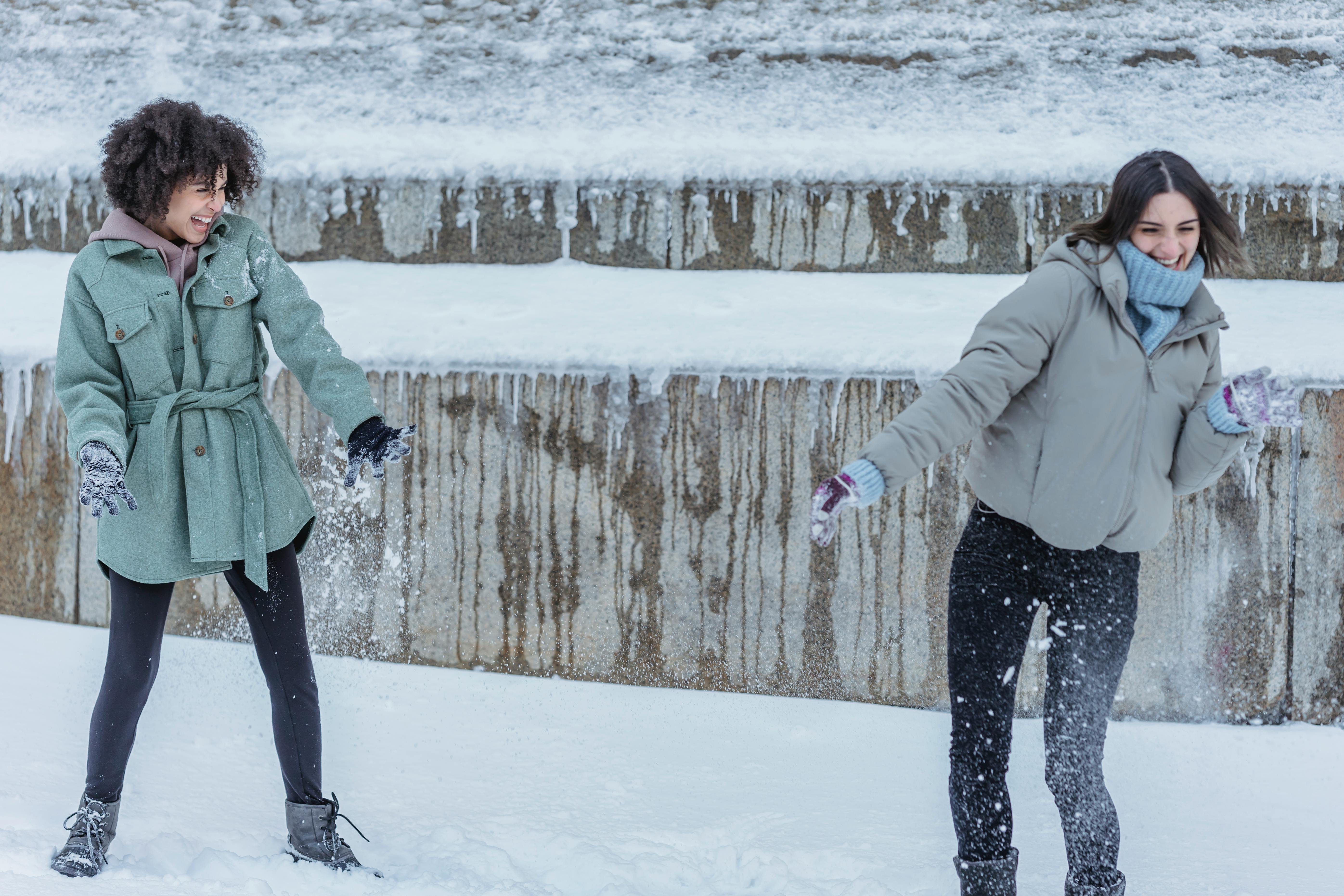 diverse friends playing snowball fight in snowy park