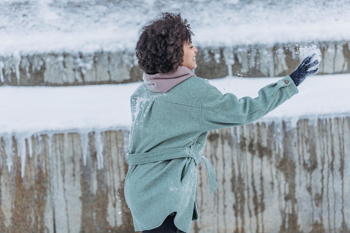 Free Side view of African American female with Afro hairstyle smiling happily while playing snowball fight Stock Photo