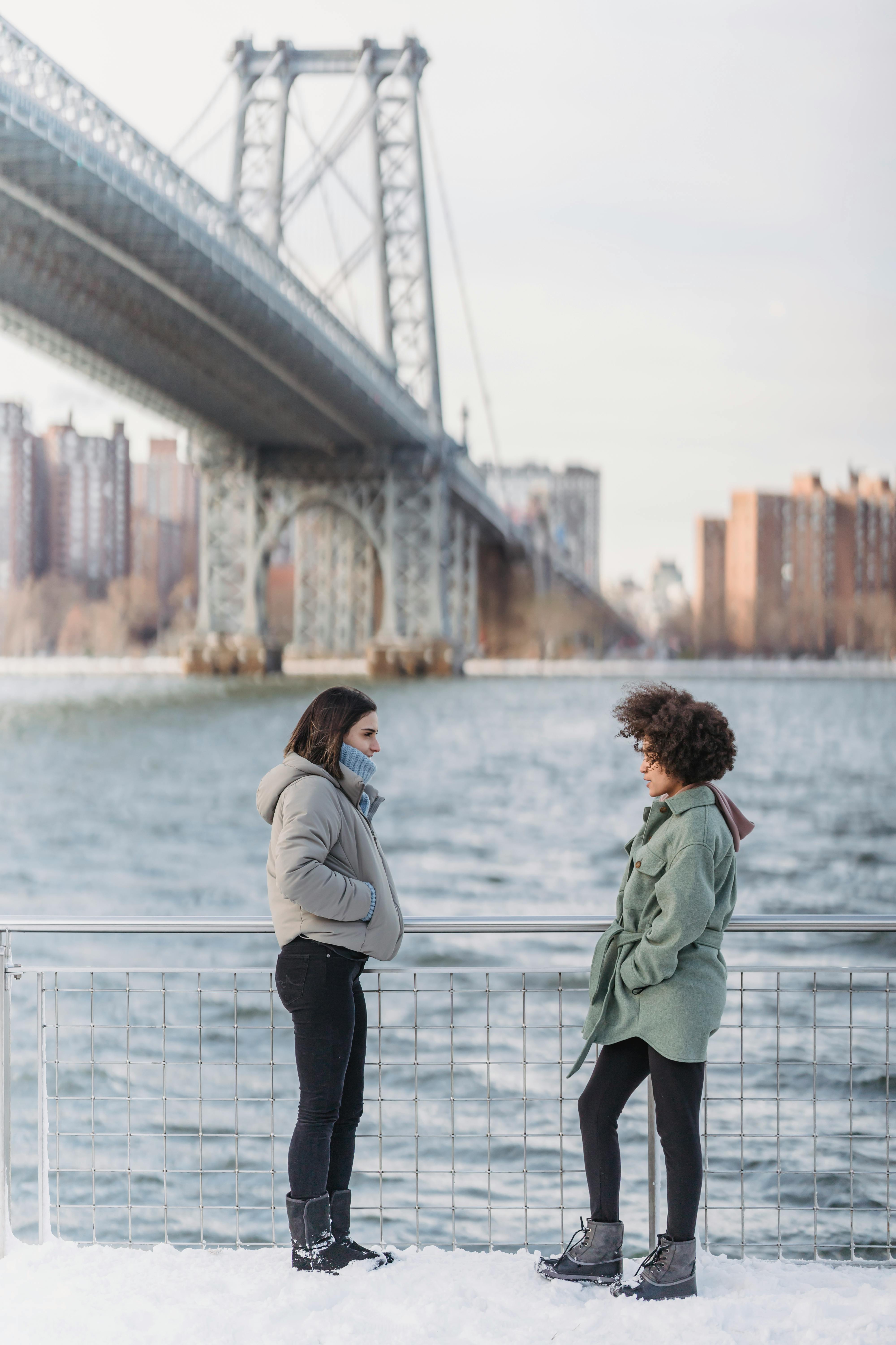 young women chatting on embankment in urban city