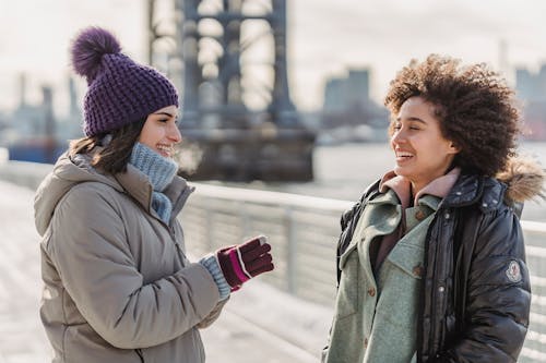 Free Carefree diverse women in outerwear chatting on city embankment Stock Photo