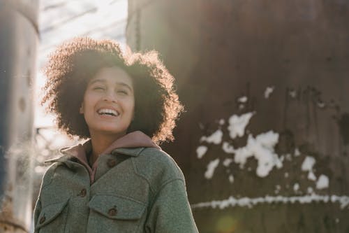 Free Cheerful ethnic woman laughing on snowy winter street Stock Photo