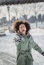 Expressive ethnic woman throwing snowball in winter park