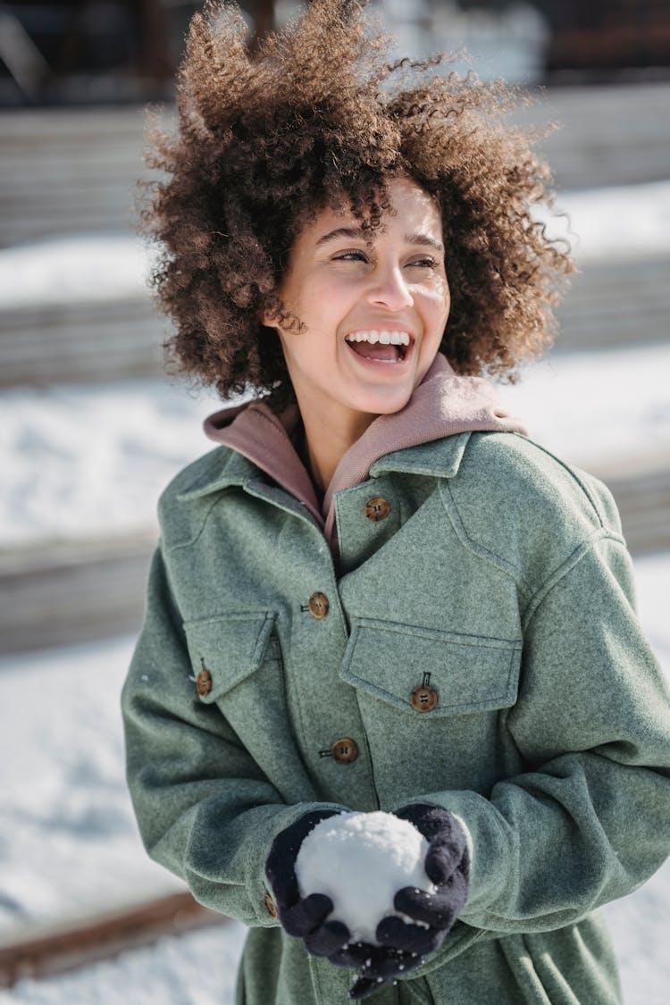 Excited Ethnic Woman With Snowball In Winter Park