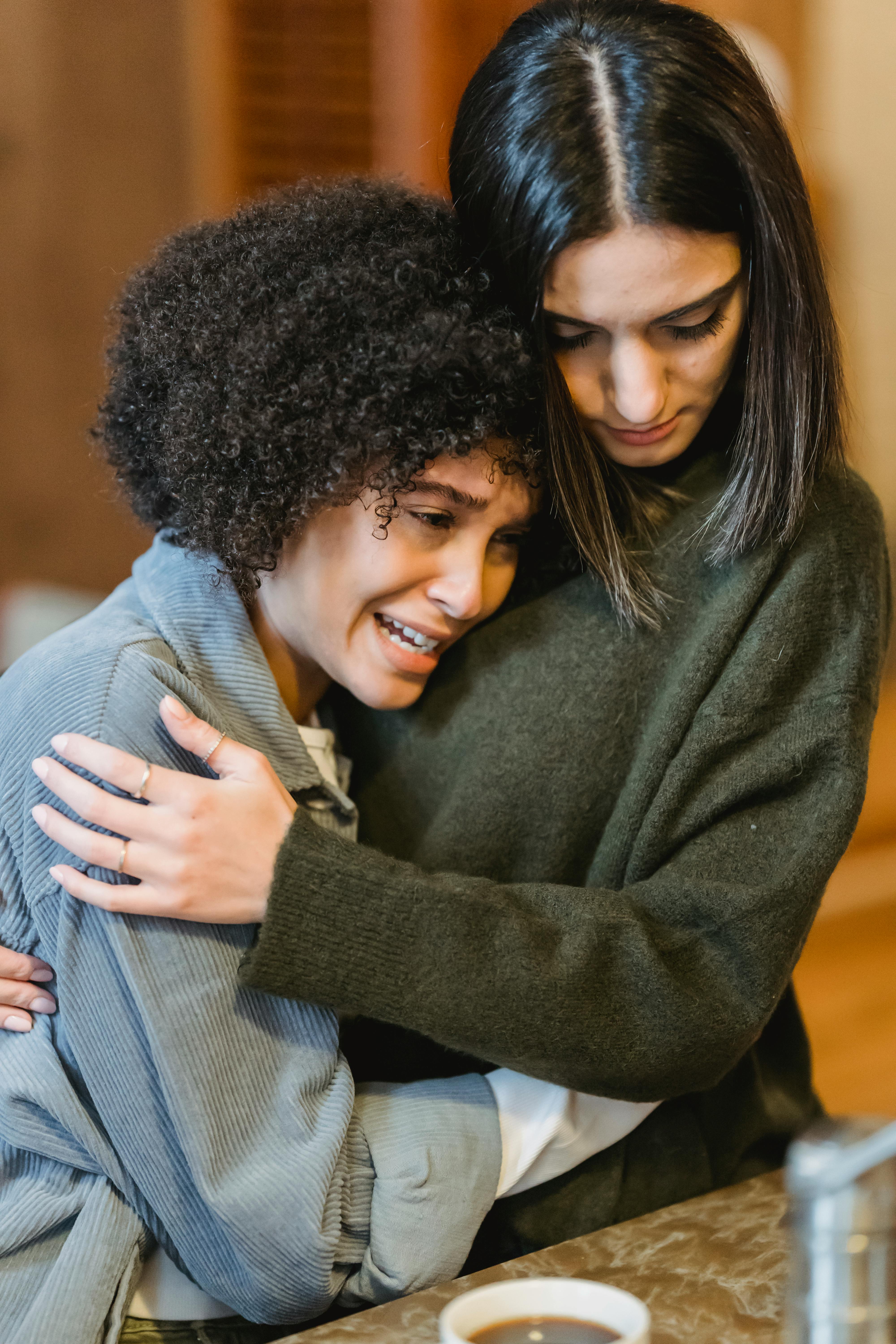 young unhappy woman crying and hugging empathetic female friend