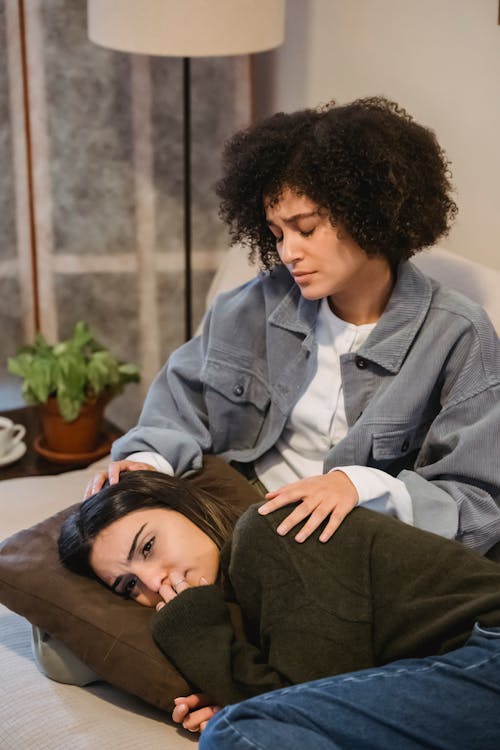 Free Young melancholic woman lying on couch near black female friend Stock Photo