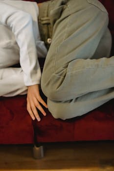 A person in casual attire relaxing indoors on a red sofa, embodying tranquility and comfort.