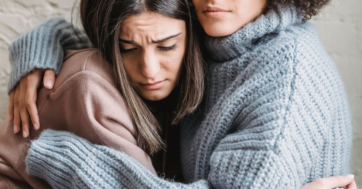 Both Crying Sad multiracial girlfriends crying while hugging each other in room ...