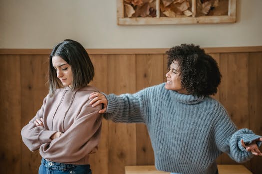 Two young women in a serious discussion in a cozy room setting.