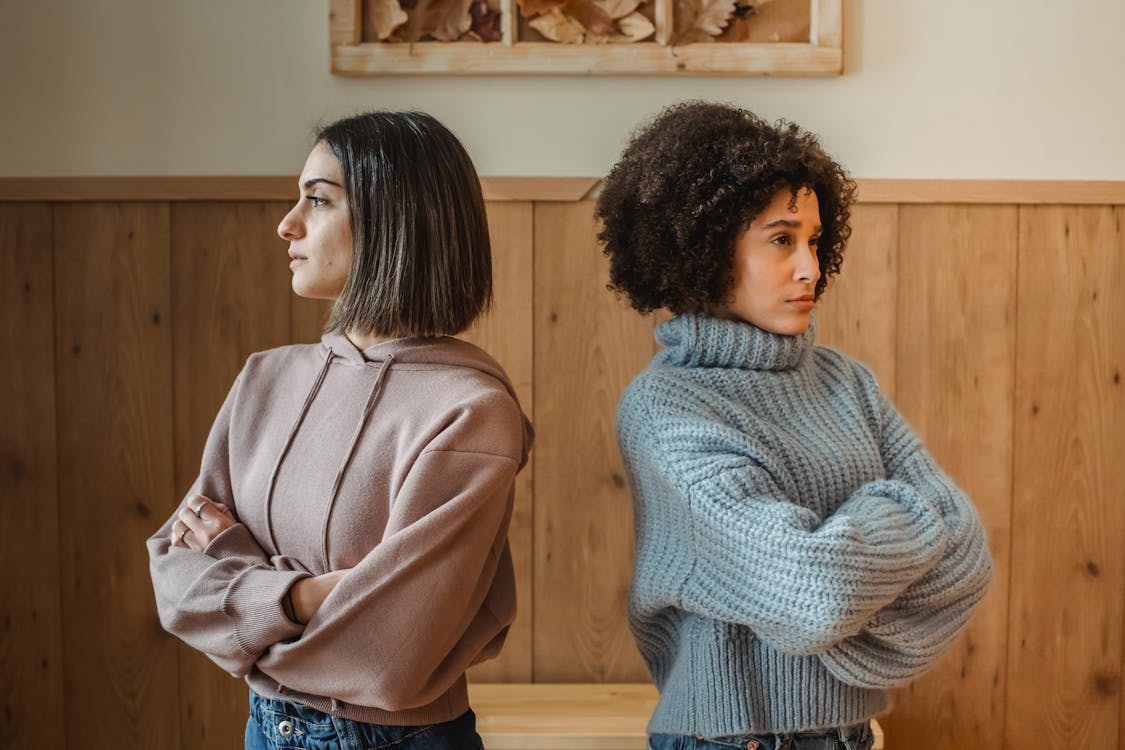 Free Unhappy multiethnic women standing back to back in room Stock Photo