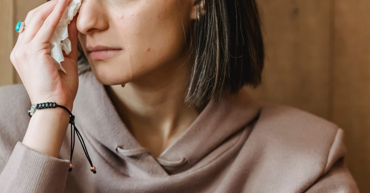 Sad female with tissue crying near wall · Free Stock Photo