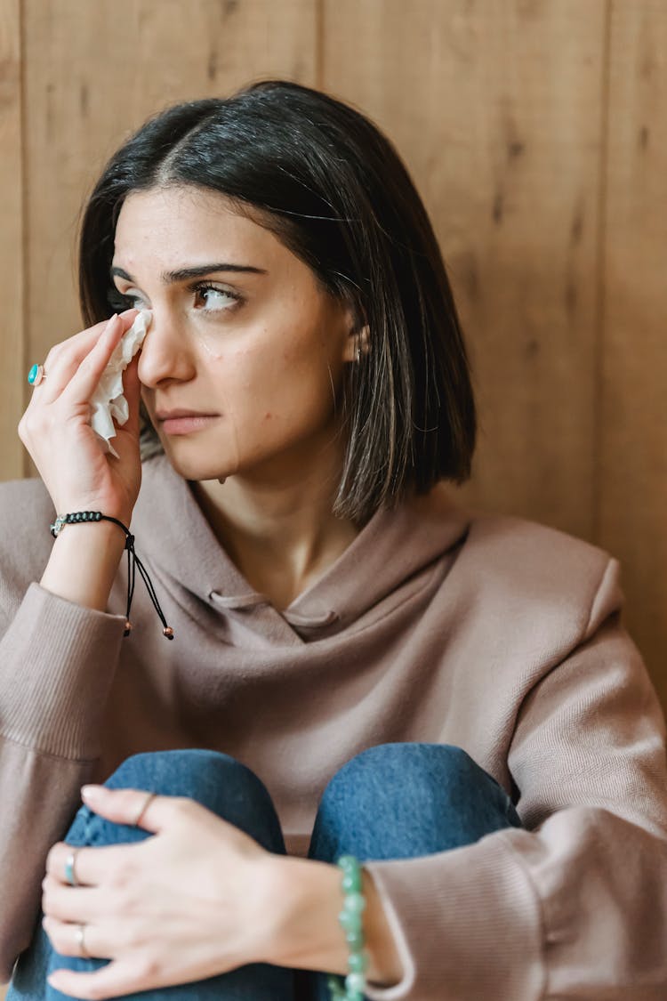 Sad Female With Tissue Crying Near Wall