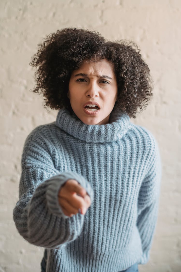 Unhappy Ethnic Woman Pointing Finger At Camera In Room