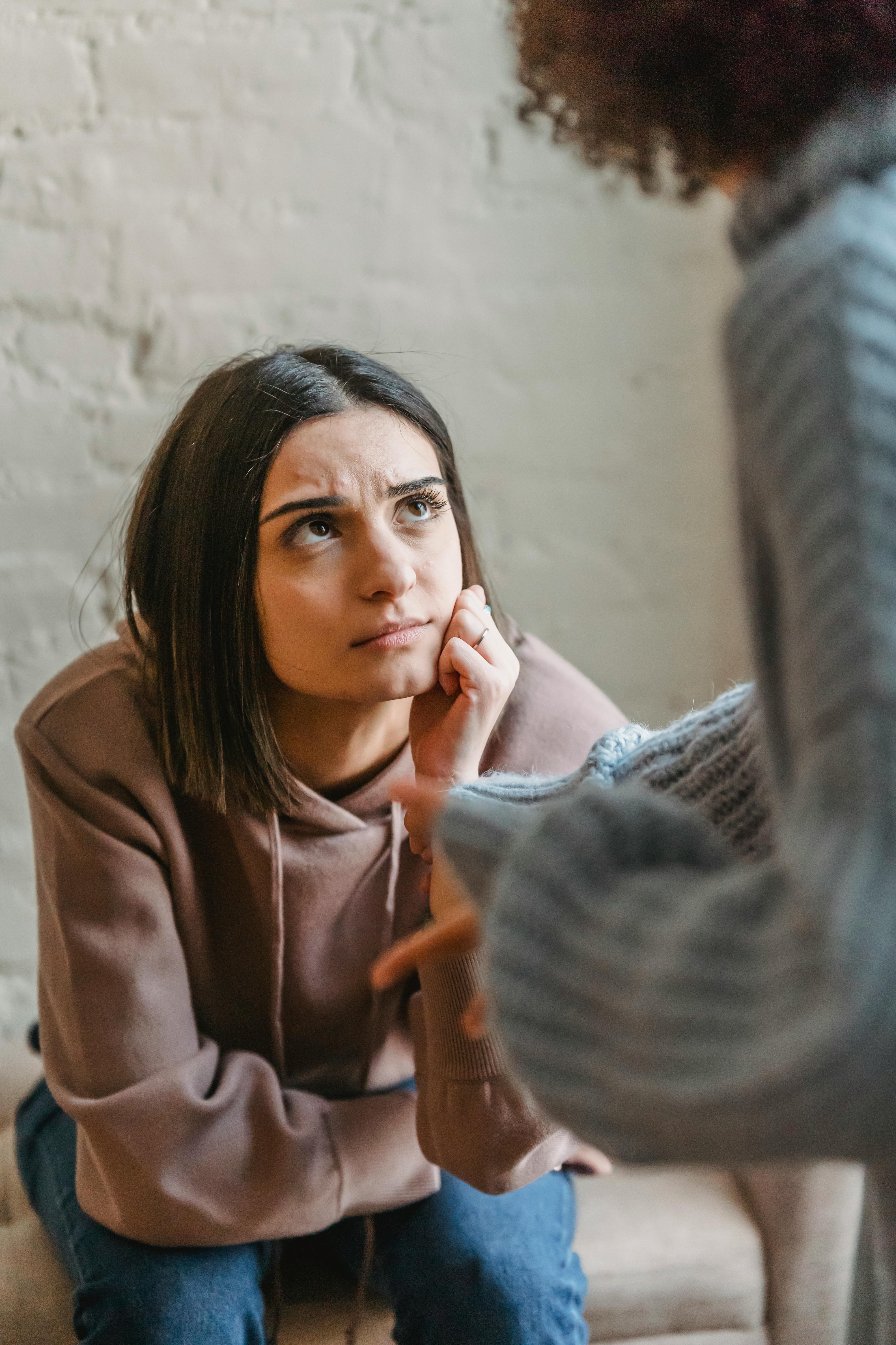 young woman sitting on sofa and listening to friend