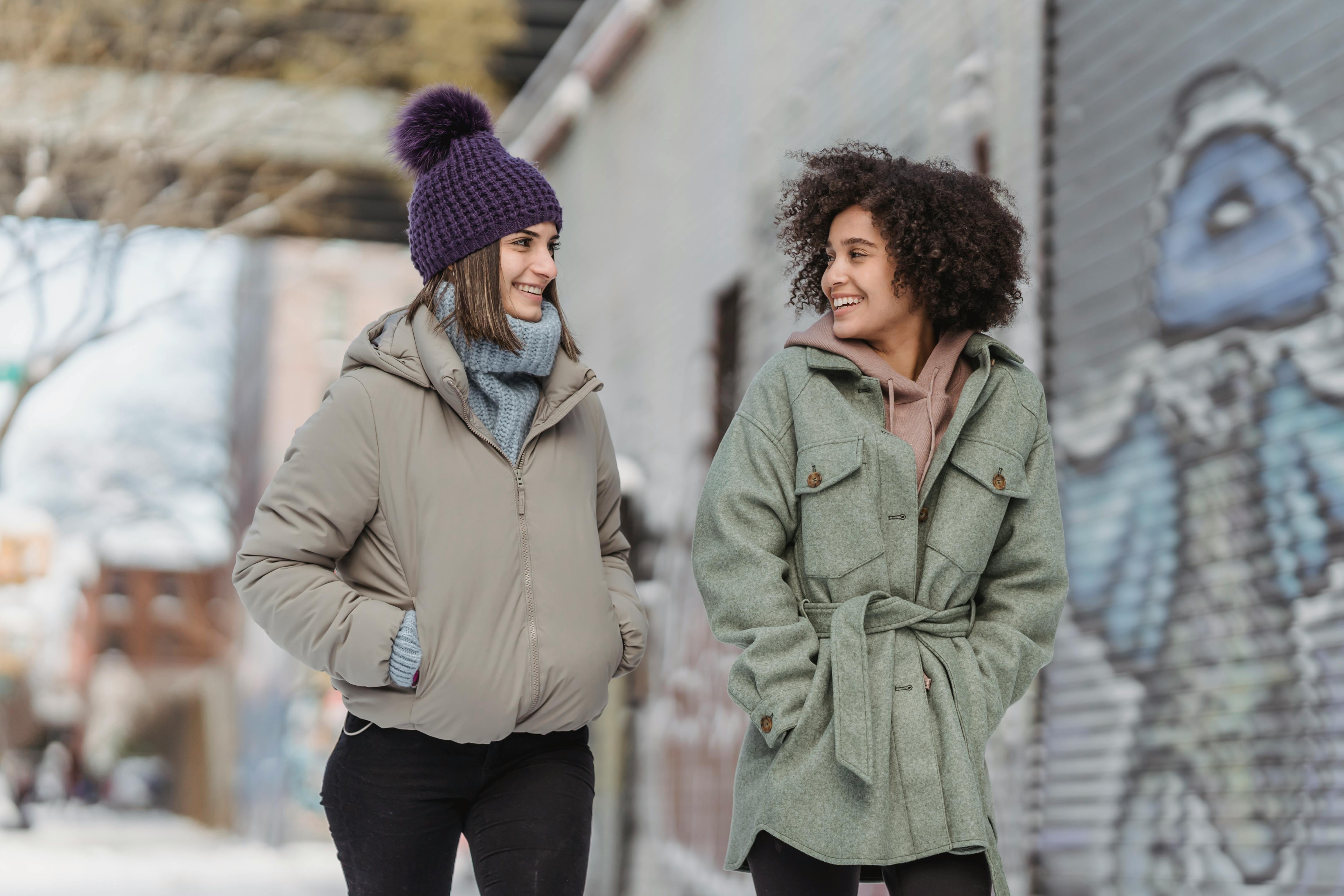 diverse women in warm clothes walking on street