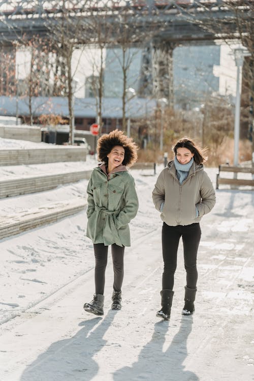 Cheerful diverse women walking on snowy street