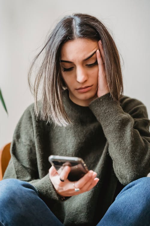 Une femme regarde son téléphone, déçue parce qu'elle a des problèmes avec le son de Instagram qui ne fonctionne pas.