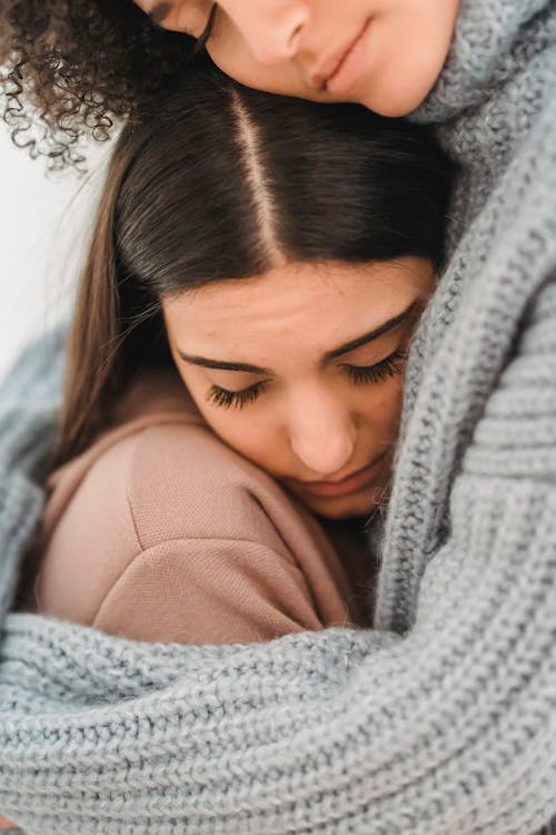 Upset diverse women hugging in room