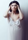 Adult woman with dark hair and makeup in nightwear looking at camera with confident gaze