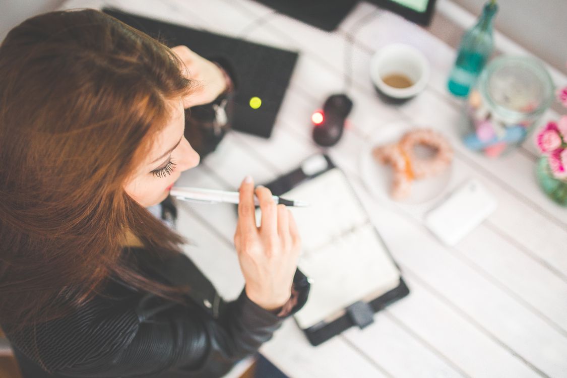A woman thoughtfully preparing notes at her study desk