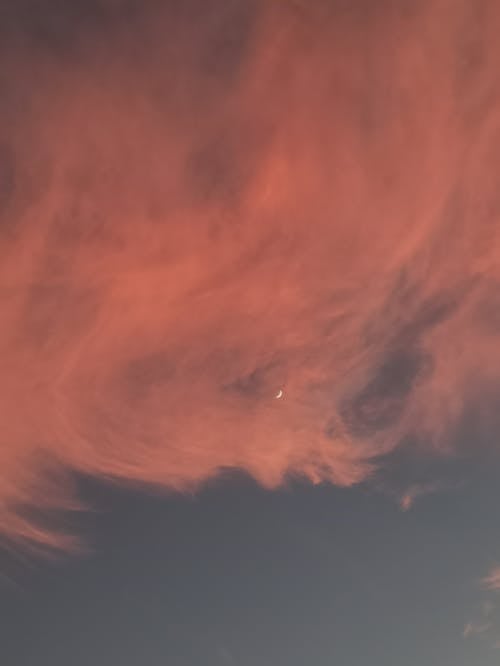 A Crescent Moon in Blue Sky Over White Clouds