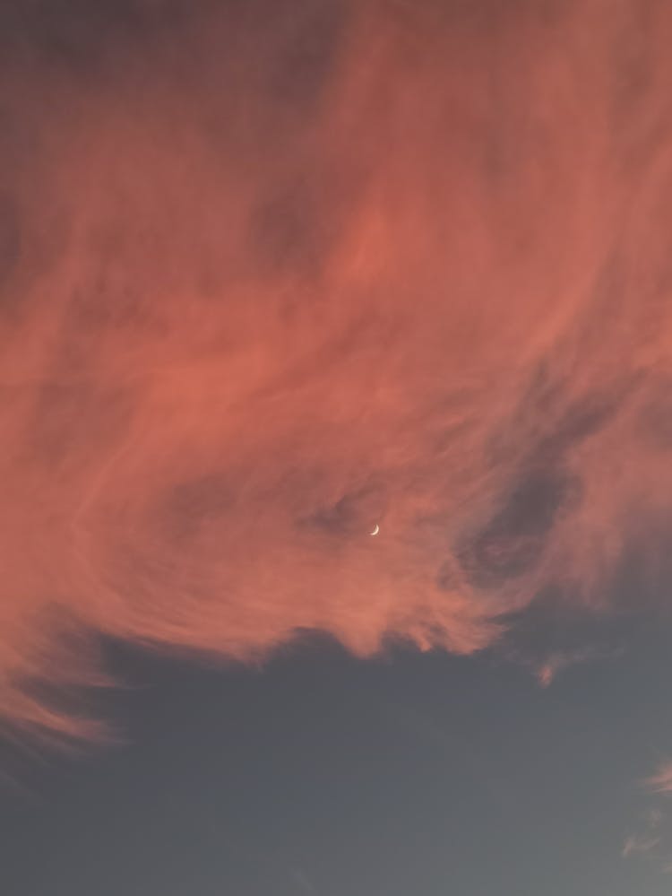 A Crescent Moon In Blue Sky Over White Clouds