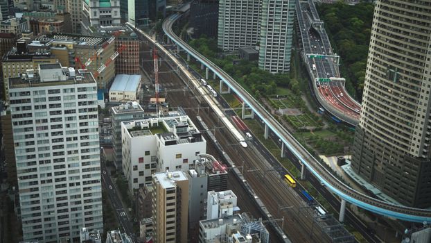Dynamic aerial shot of Tokyo's dense cityscape with bustling train lines and highways.