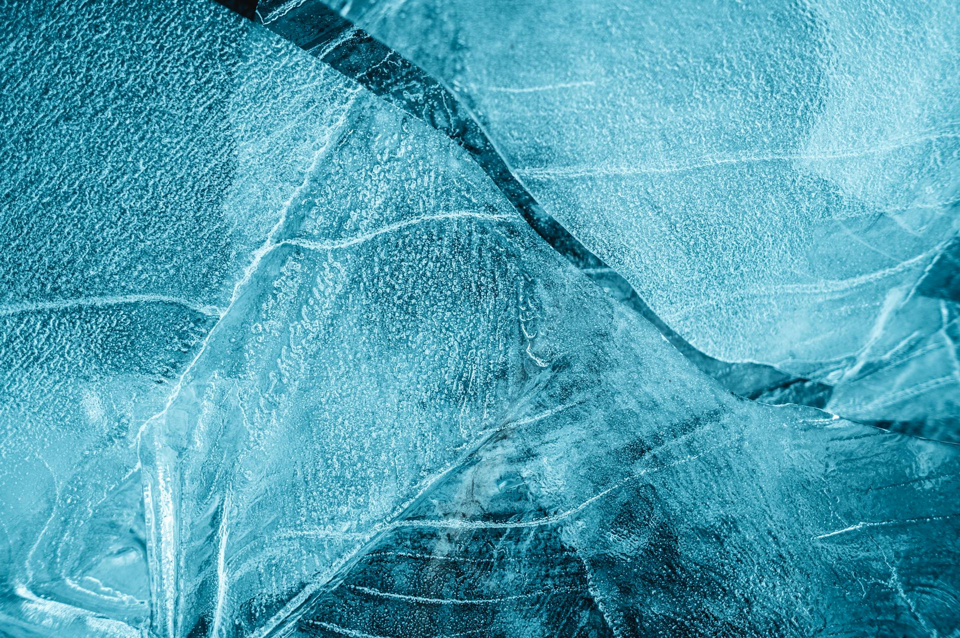 From above of frozen crystal water with thin uneven pieces of ice with cracks in daytime