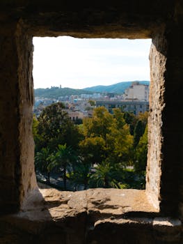 Captivating view of Palma, Mallorca through a historic stone window frame.