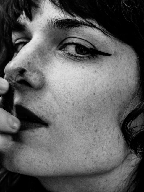 Expressive black and white portrait of a woman with bold makeup and freckles.