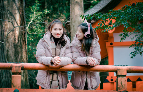 Free Two women in winter jackets having fun outdoors, one with headphones. Stock Photo