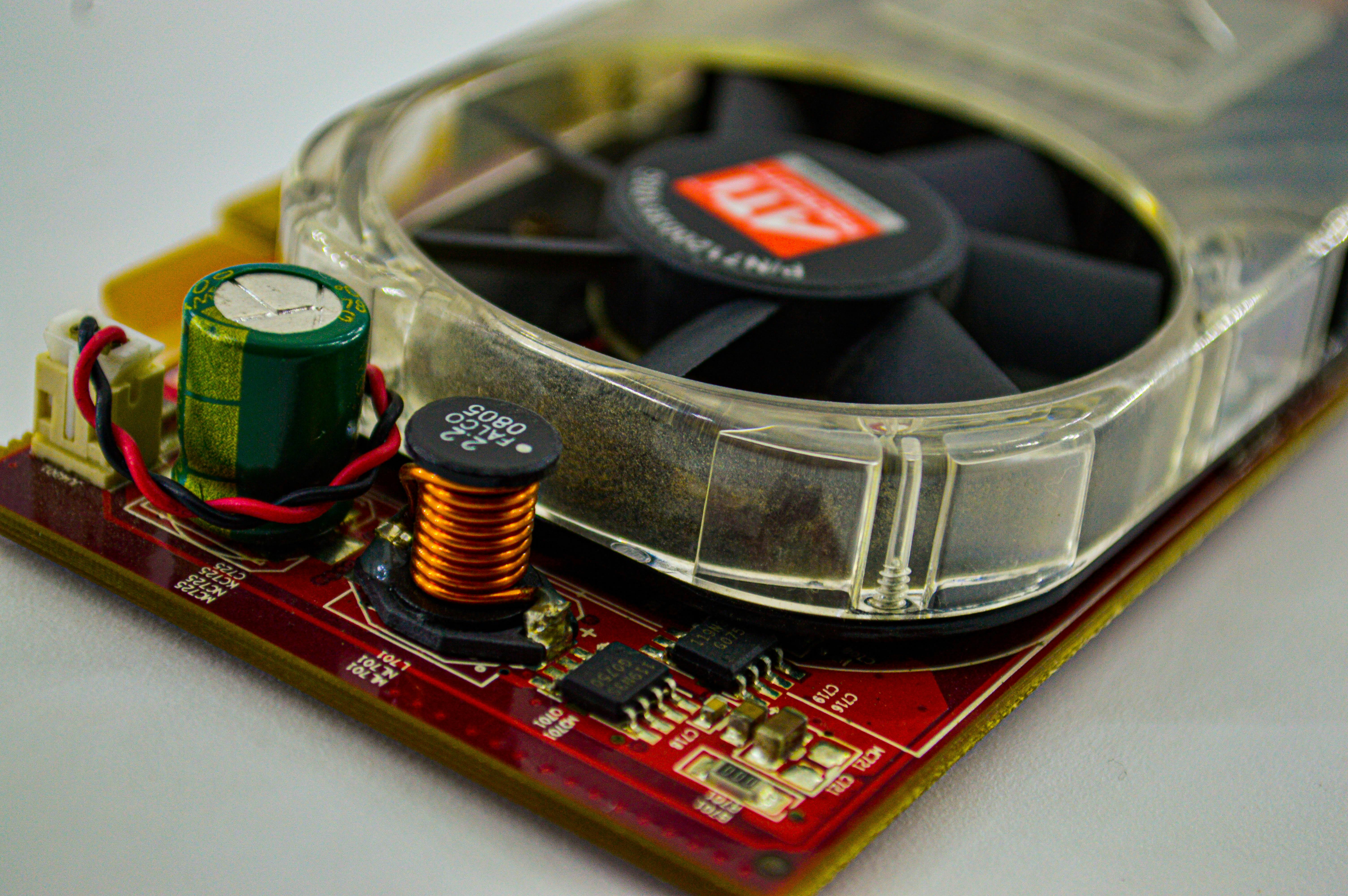 Detailed view of a cooling fan and capacitor on a computer circuit board, showcasing electronic components.