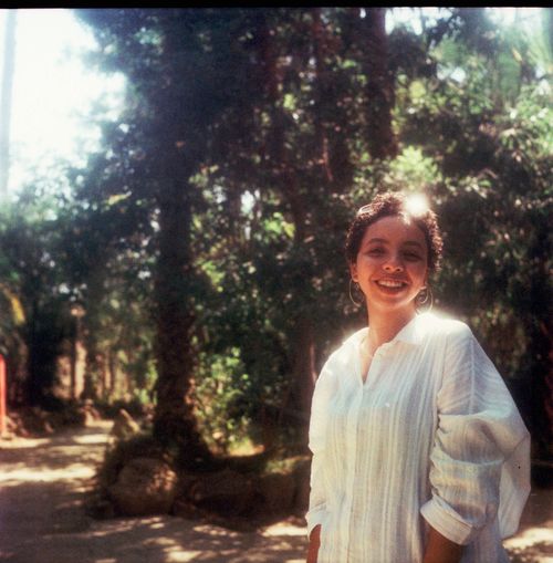 Free A vintage portrait of a smiling woman outdoors in a lush Egyptian garden setting. Stock Photo