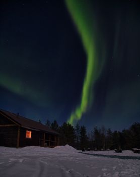 Stunning aurora borealis above a snow-covered cabin in Kiruna, Sweden.