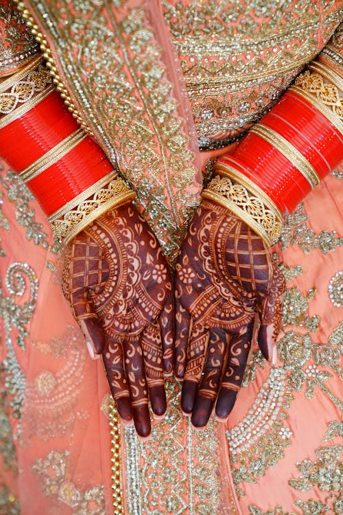 Crop Indian bride in traditional sari with henna on hands
