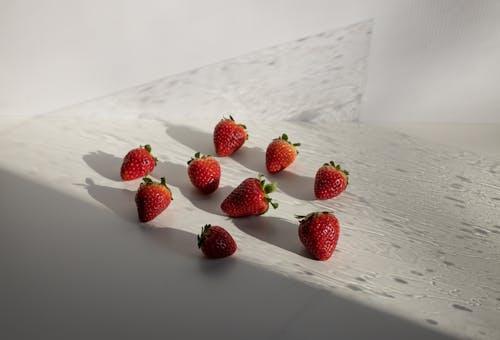 High angle of fresh ripe red strawberries scattered on white table on sunny day