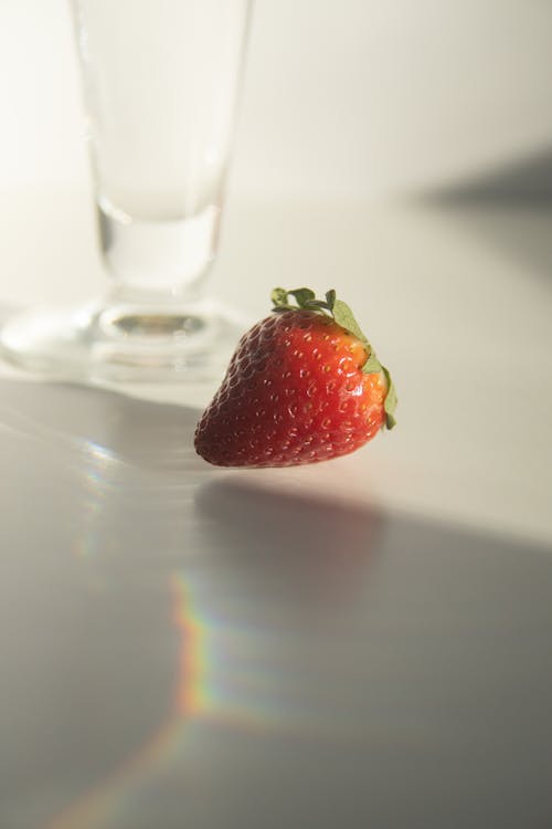 Fresh strawberry placed on table near water glass