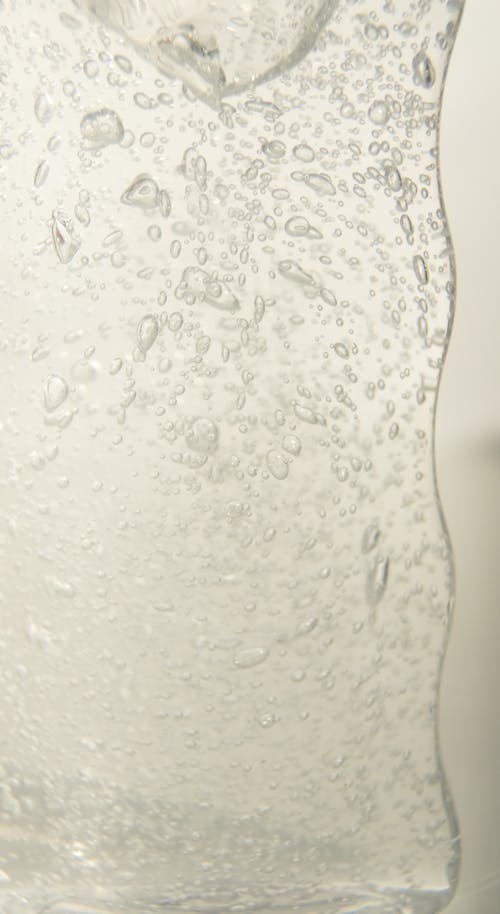 Glass jar with water with bubbles against white background