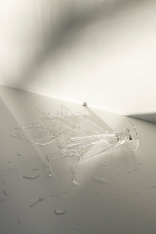 Free From above of broken glass with spilled water on white table in daylight Stock Photo