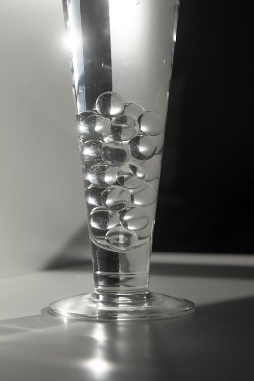 Glass of water with decorative balls placed on counter